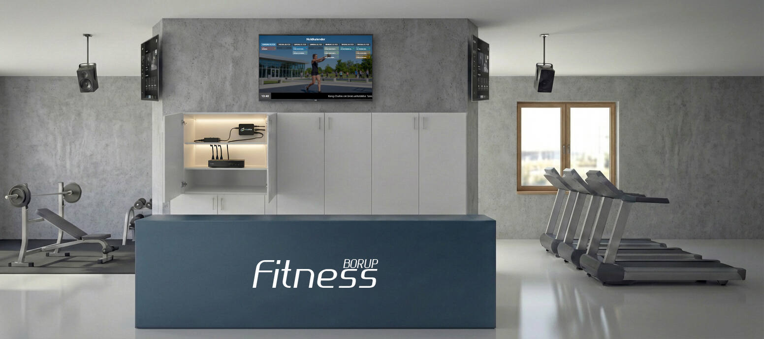Infoskærm monteret på væggen i et foreningsdrevet fitnesscenter